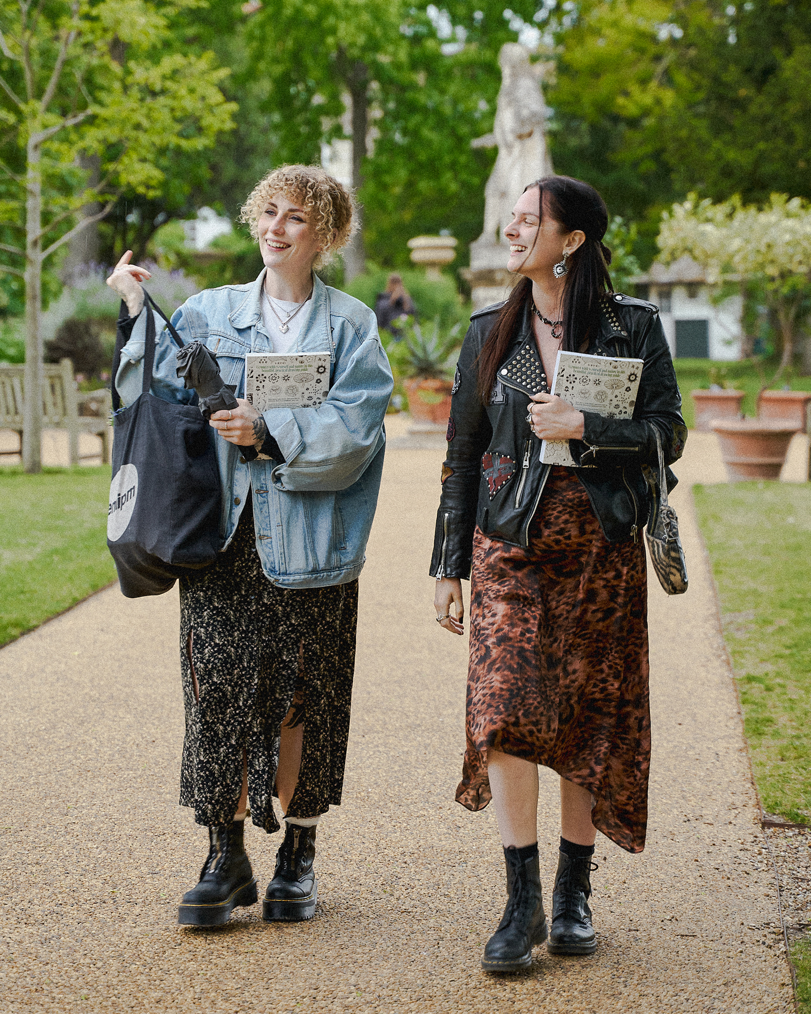 Two visitors walking through Chelsea Physic Garden while carrying copies of Beyond Botanical.