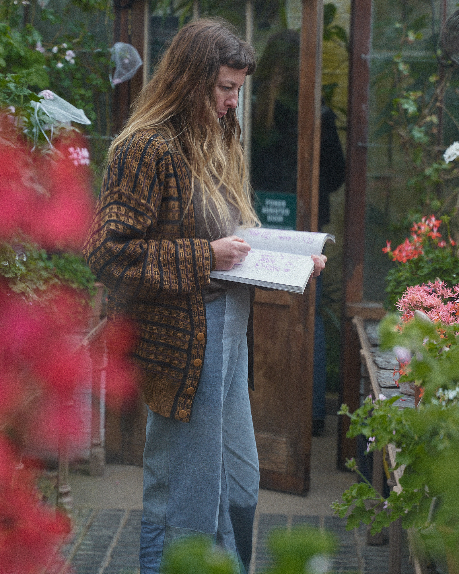 A participant drawing in Beyond Botanical beside flowering plants at Chelsea Physic Garden.