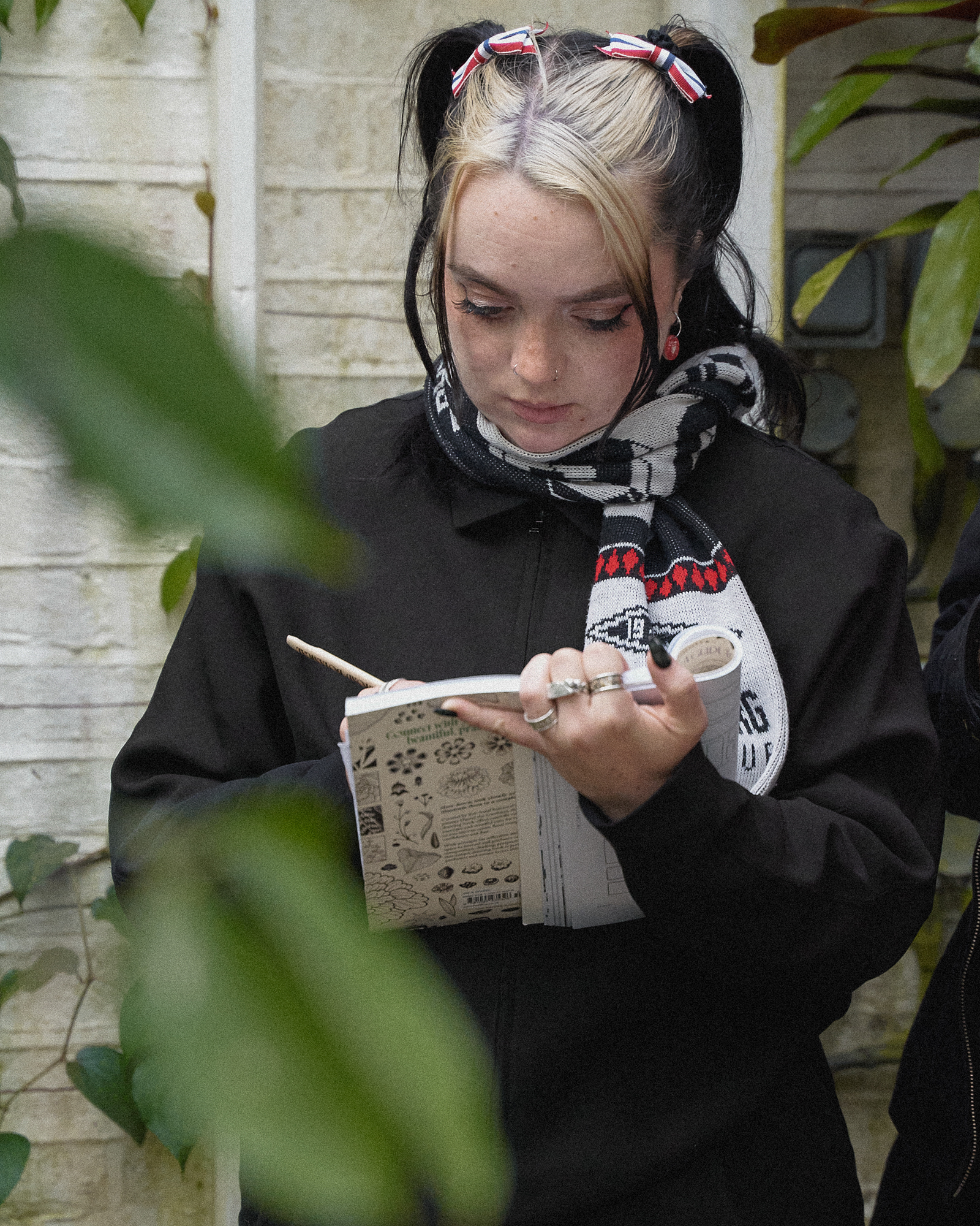 A participant drawing in a copy of Beyond Botanical among plants at Chelsea Physic Garden.