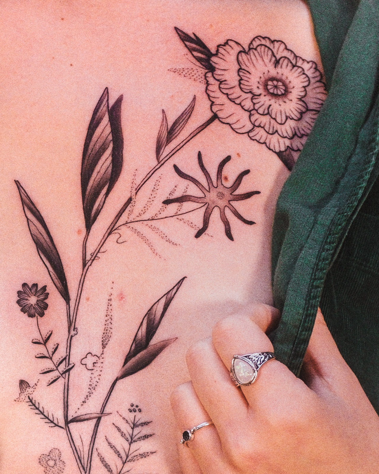 Botanical tattoo across the ribs and side torso with flowers, leaves and small branching forms