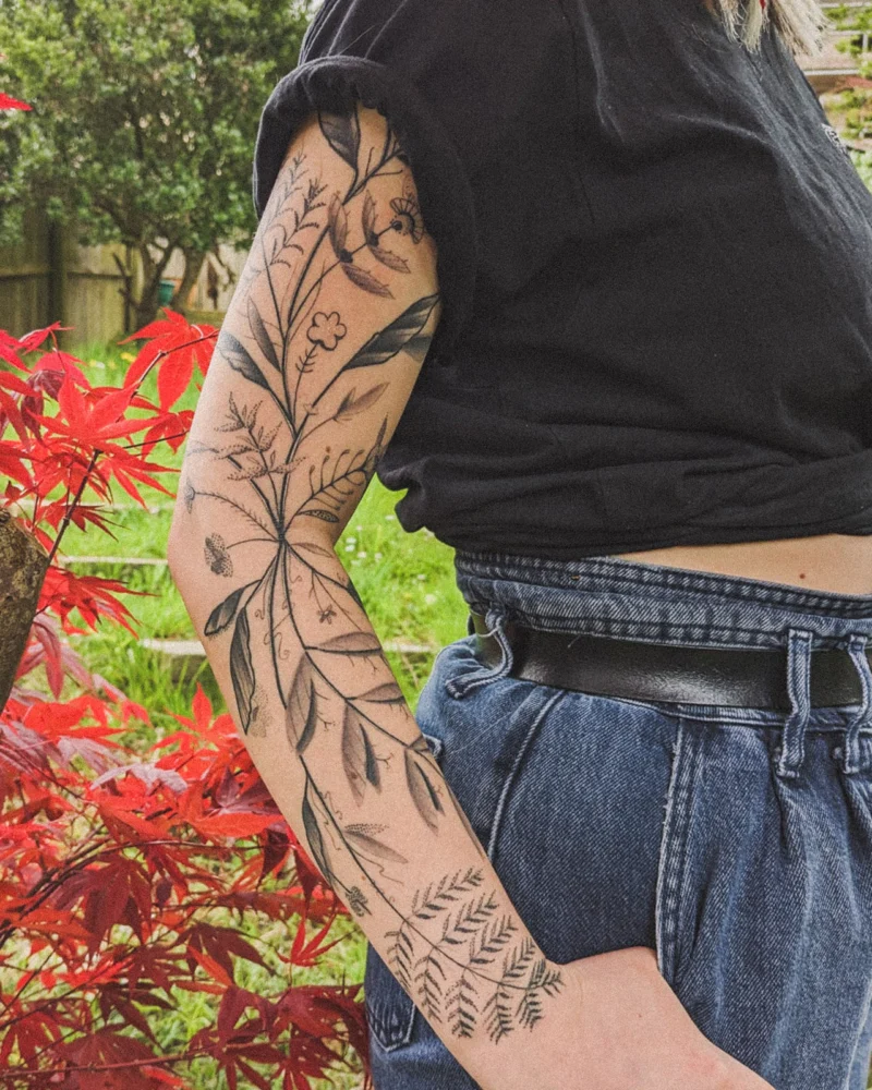Freehand botanical tattoo across the arms