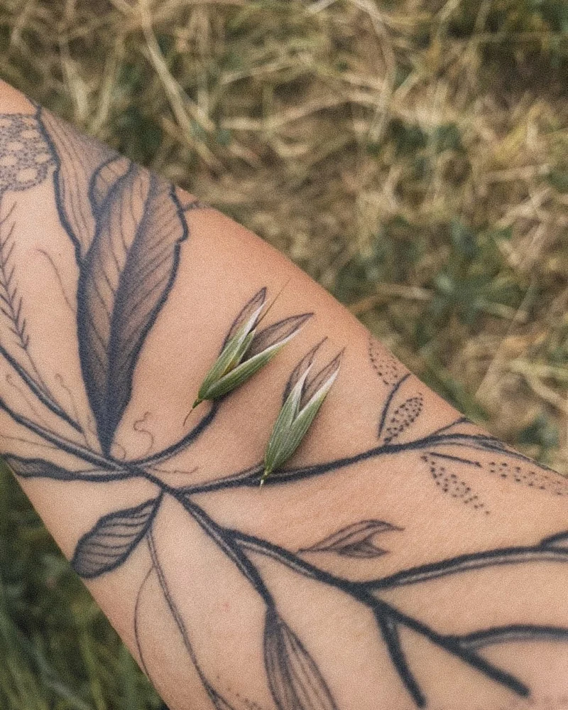 Small grass seed heads placed over corresponding lines in a botanical arm tattoo