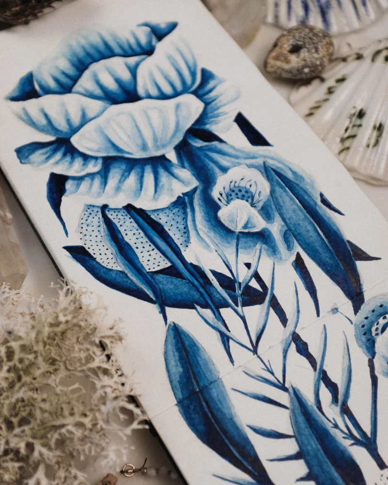 A blue botanical painting on paper arranged with lichen, shells and coastal specimens.