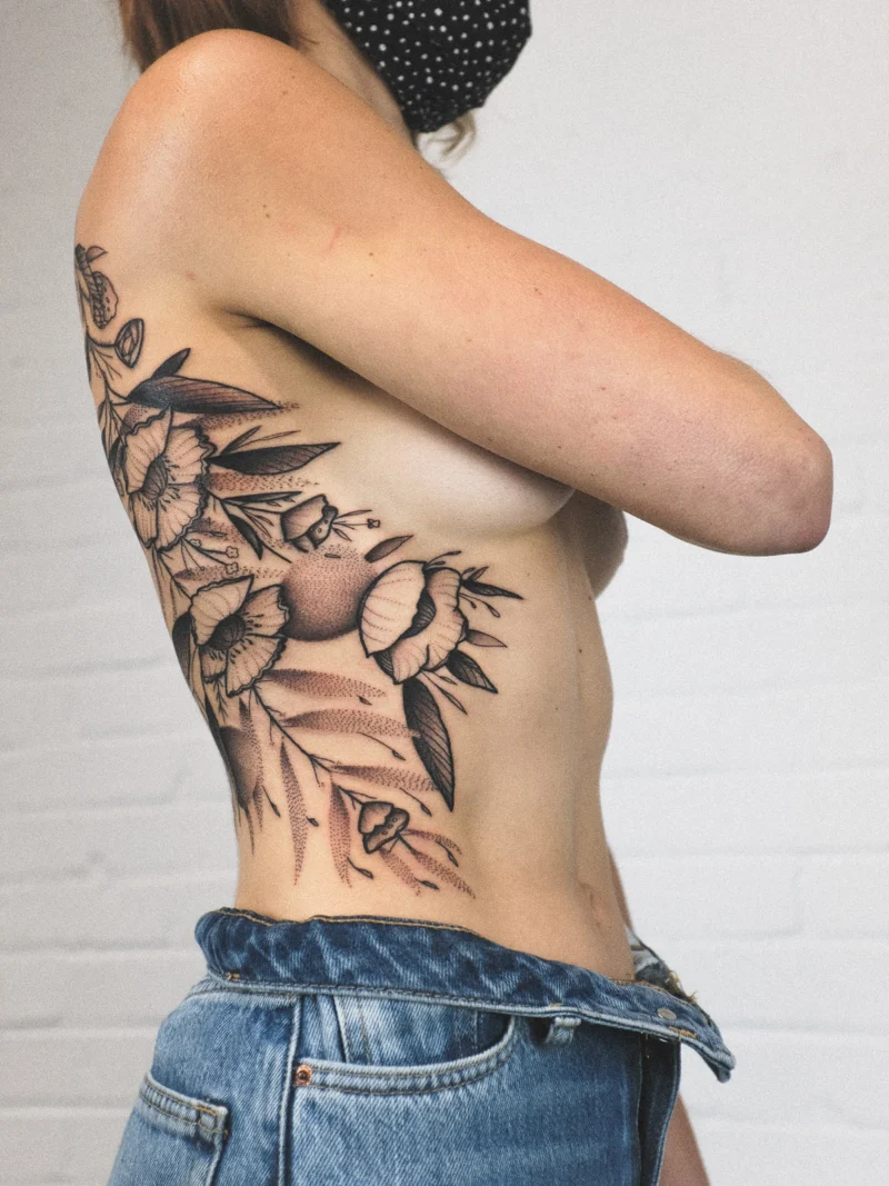 Another view of a freehand botanical tattoo across the ribs