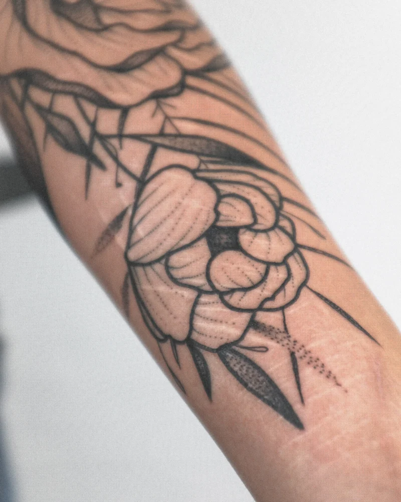 Detail view of a freehand botanical tattoo across the arms
