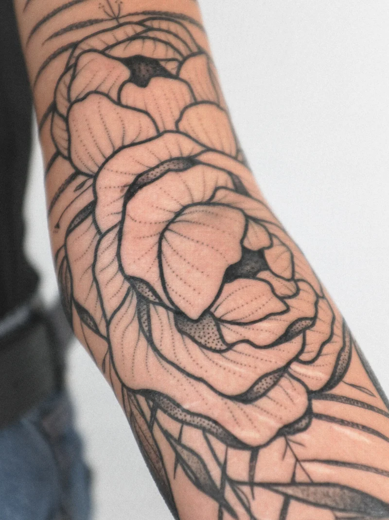 Detail view of a freehand botanical tattoo across the arms