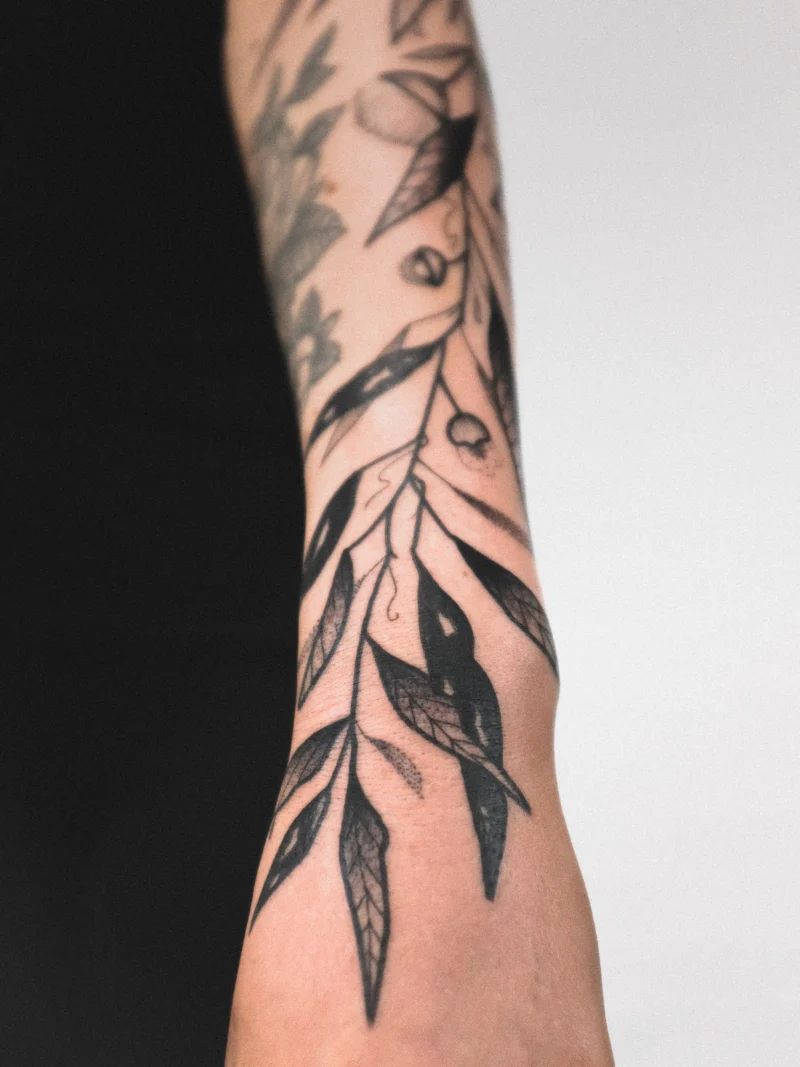 Detail view of a freehand botanical tattoo across the arms