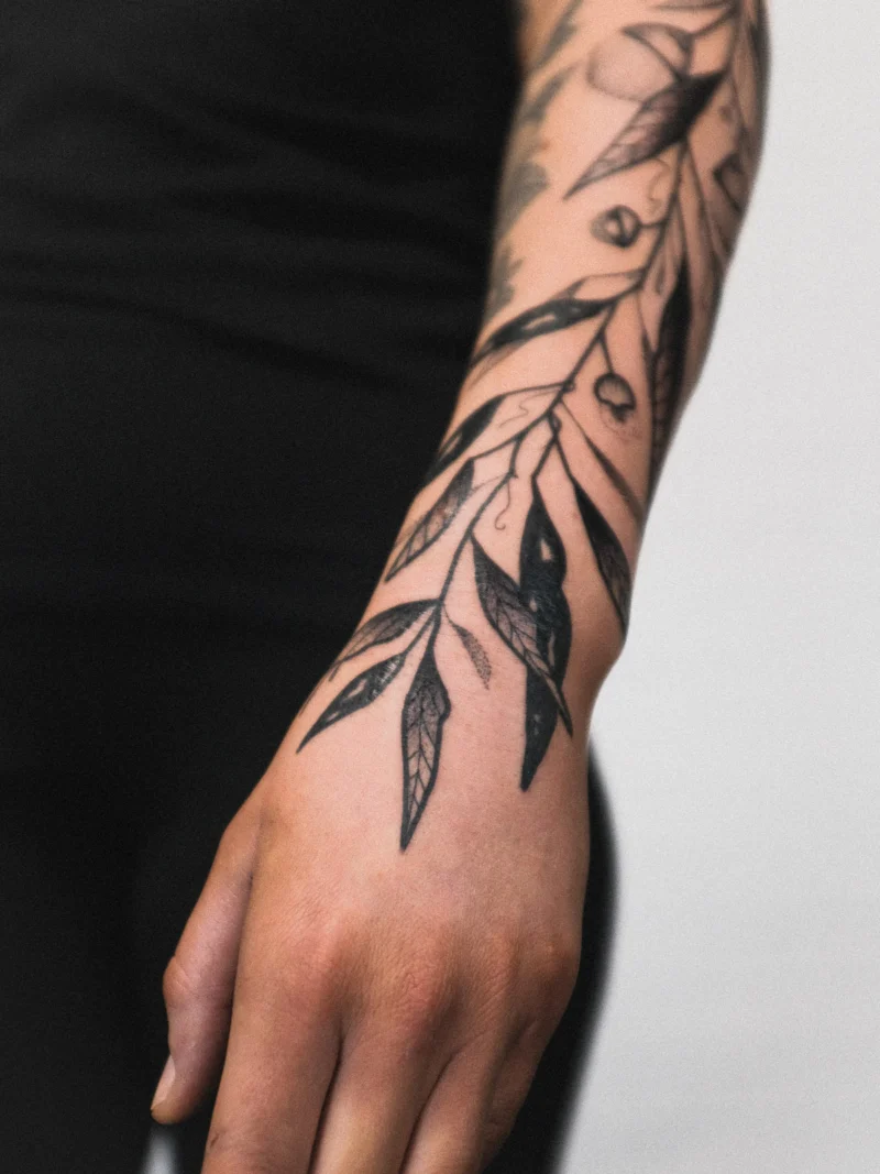 Detail view of a freehand botanical tattoo across the arms