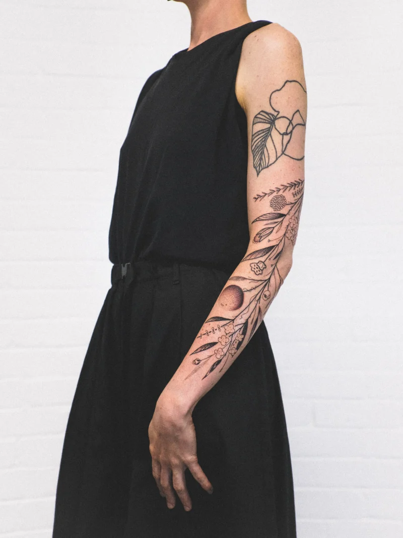 Freehand botanical tattoo across the arms