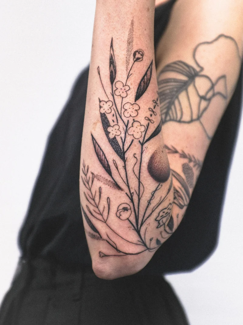 Detail view of a freehand botanical tattoo across the arms