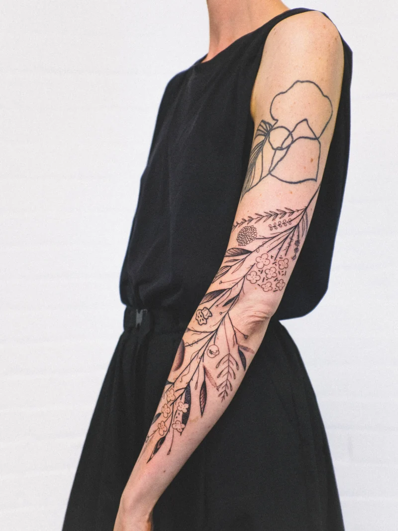 Another view of a freehand botanical tattoo across the arms