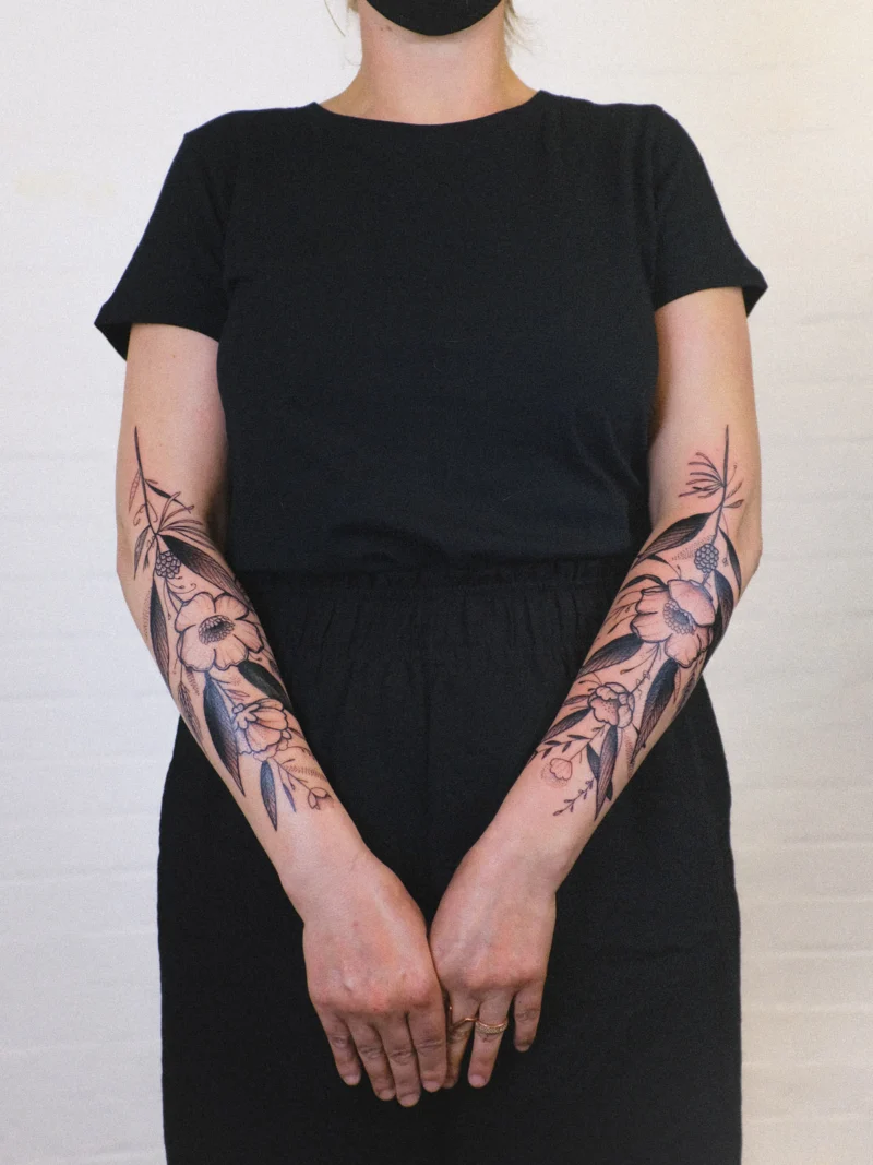 Freehand botanical tattoo across the arms