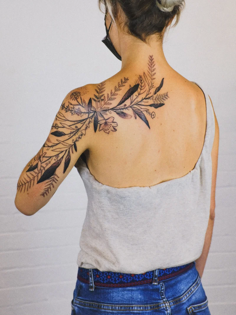 Freehand botanical tattoo across the arms and back