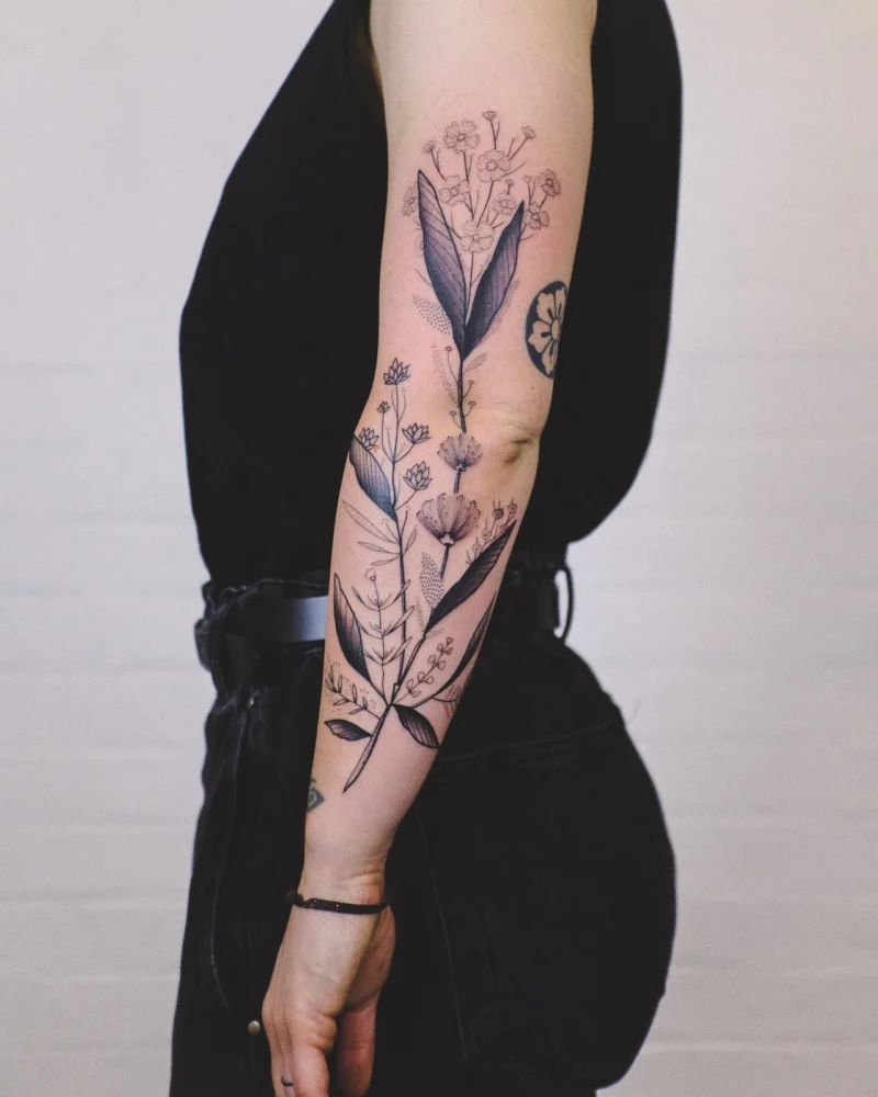 Freehand botanical tattoo across the arms