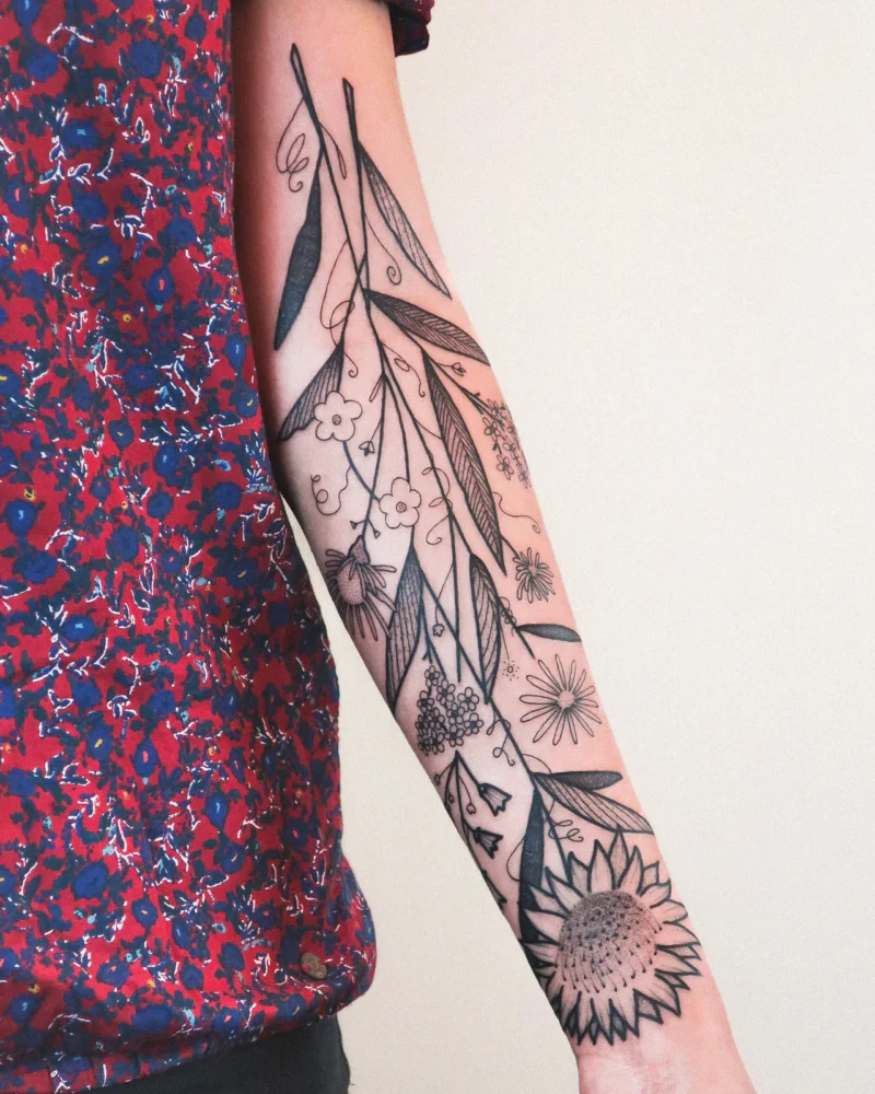 Freehand botanical tattoo across the arms