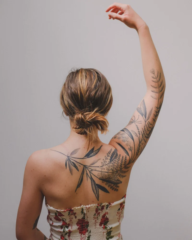 Another view of a freehand botanical tattoo across the arms and back
