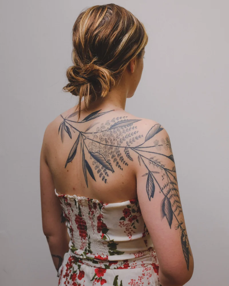 Freehand botanical tattoo across the arms and back
