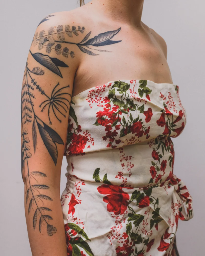 Detail view of a freehand botanical tattoo across the arms and back