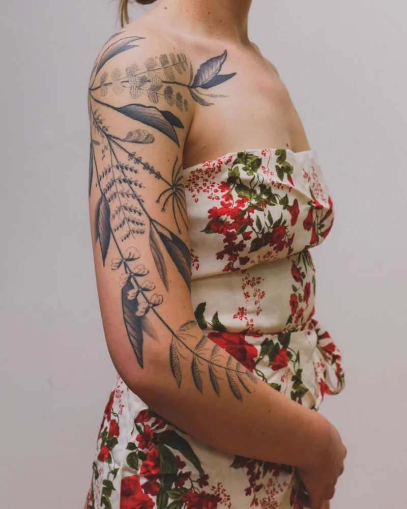 Detail view of a freehand botanical tattoo across the arms and back