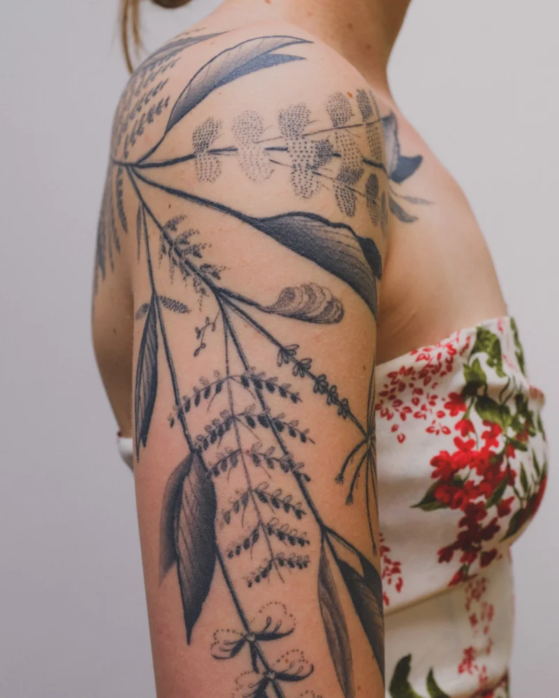 Detail view of a freehand botanical tattoo across the arms and back