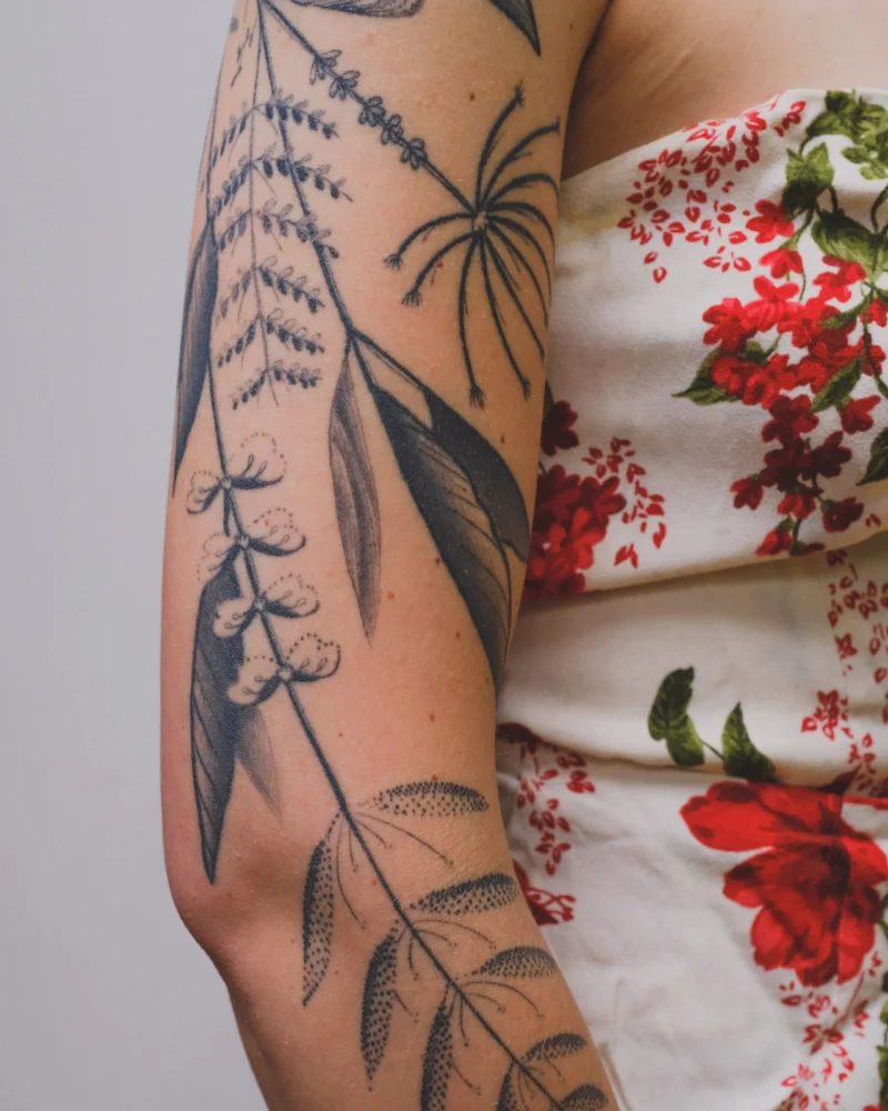 Detail view of a freehand botanical tattoo across the arms and back
