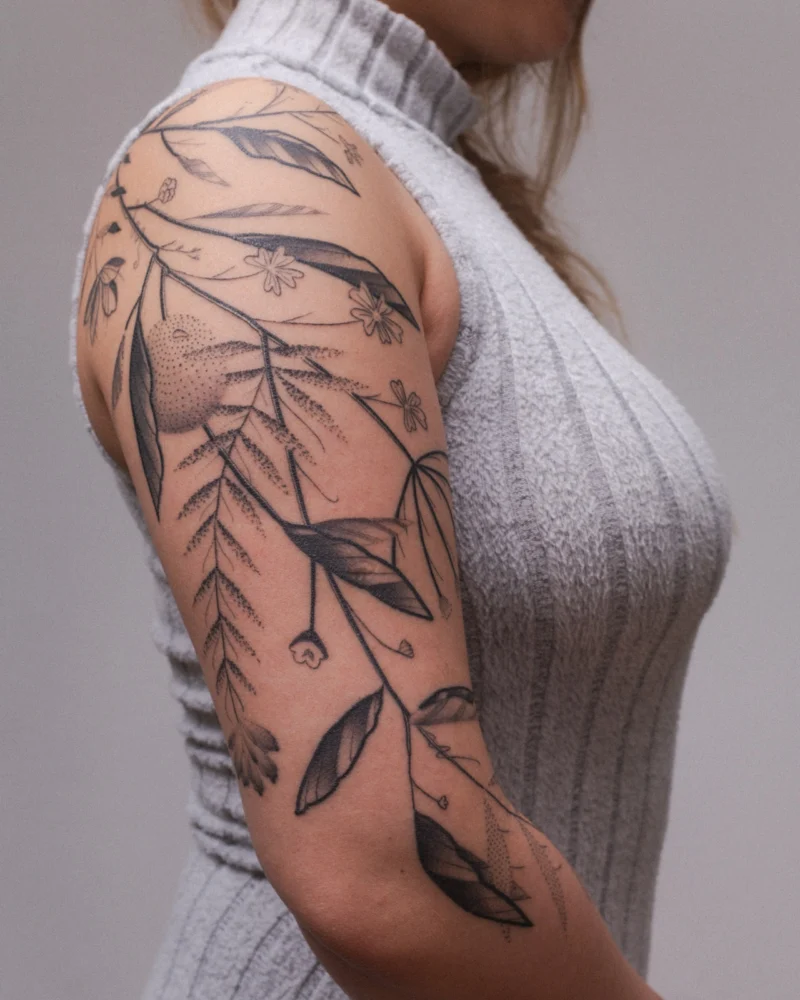 Detail view of a freehand botanical tattoo across the arms
