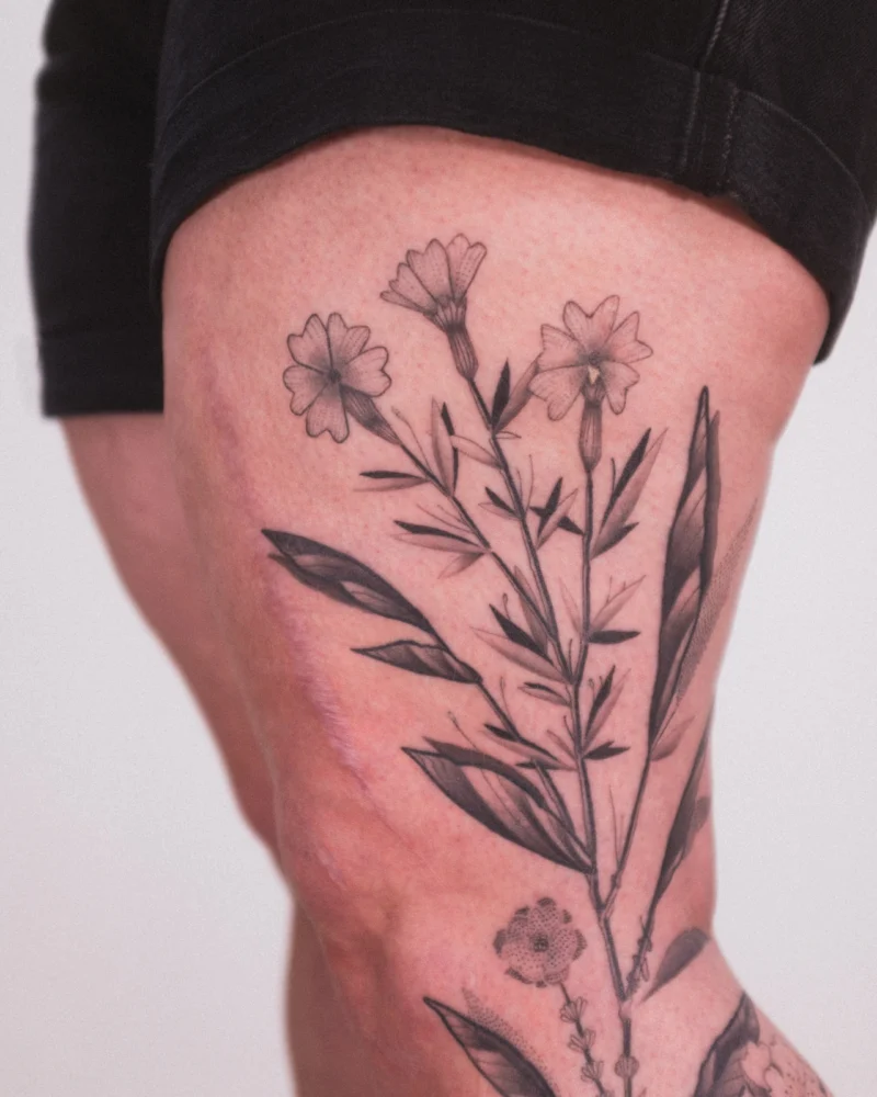 Another view of a freehand botanical tattoo across the legs
