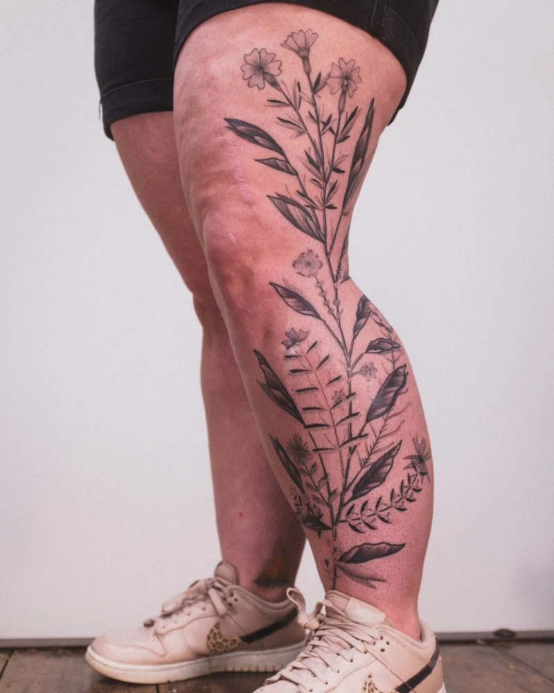 Freehand botanical tattoo across the legs