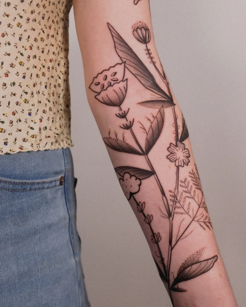 Freehand botanical tattoo across the arms