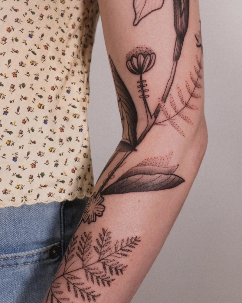 Detail view of a freehand botanical tattoo across the arms