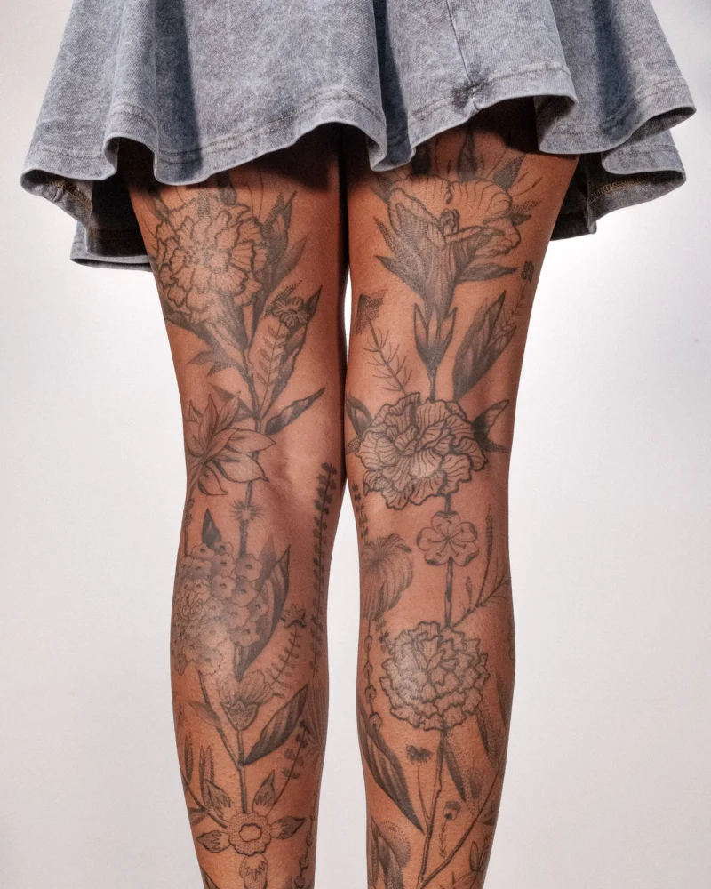 Detail view of a freehand botanical tattoo across the legs