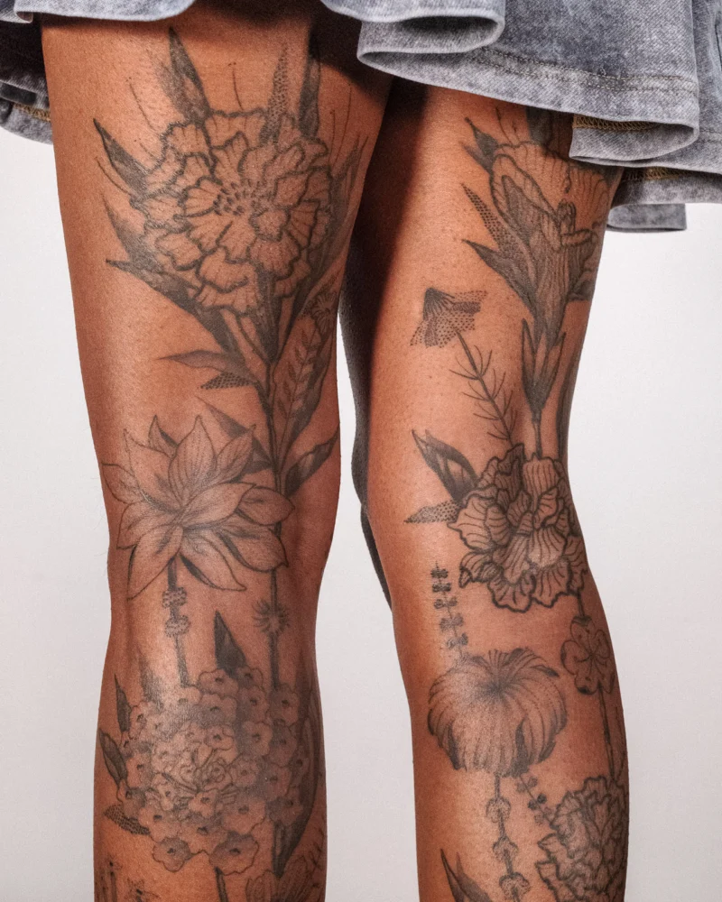 Detail view of a freehand botanical tattoo across the legs