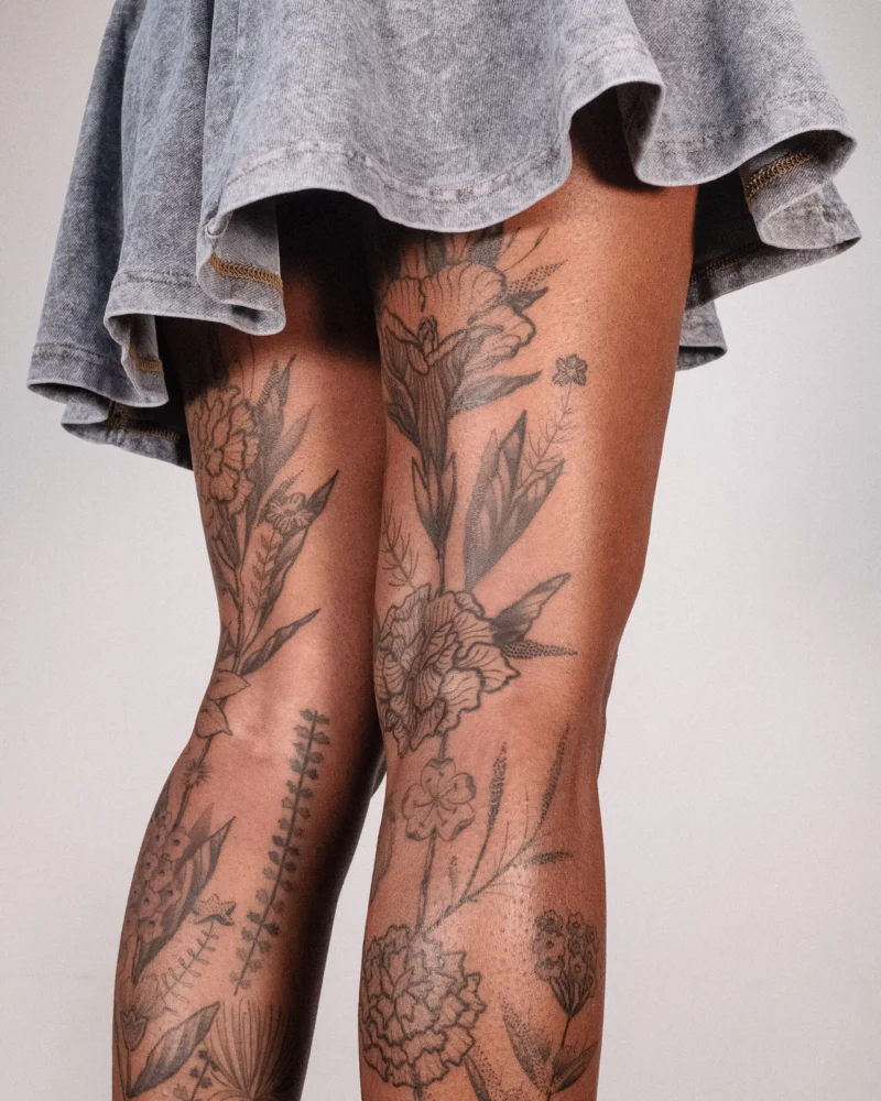 Another view of a freehand botanical tattoo across the legs