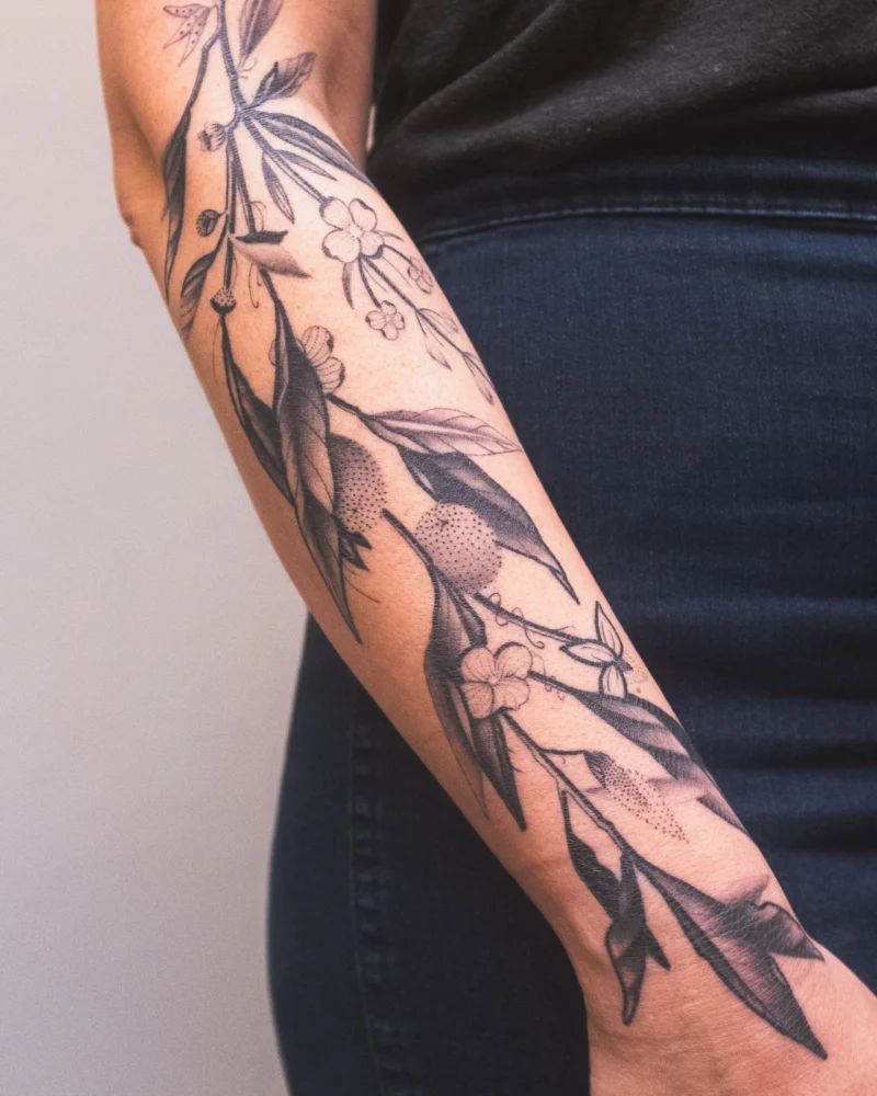 Freehand botanical tattoo across the arms