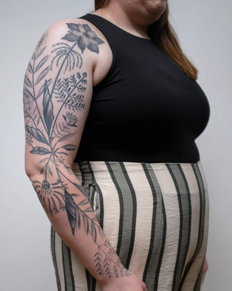 Another view of a freehand botanical tattoo across the arms