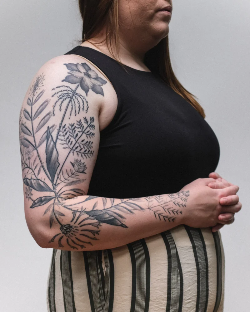 Freehand botanical tattoo across the arms