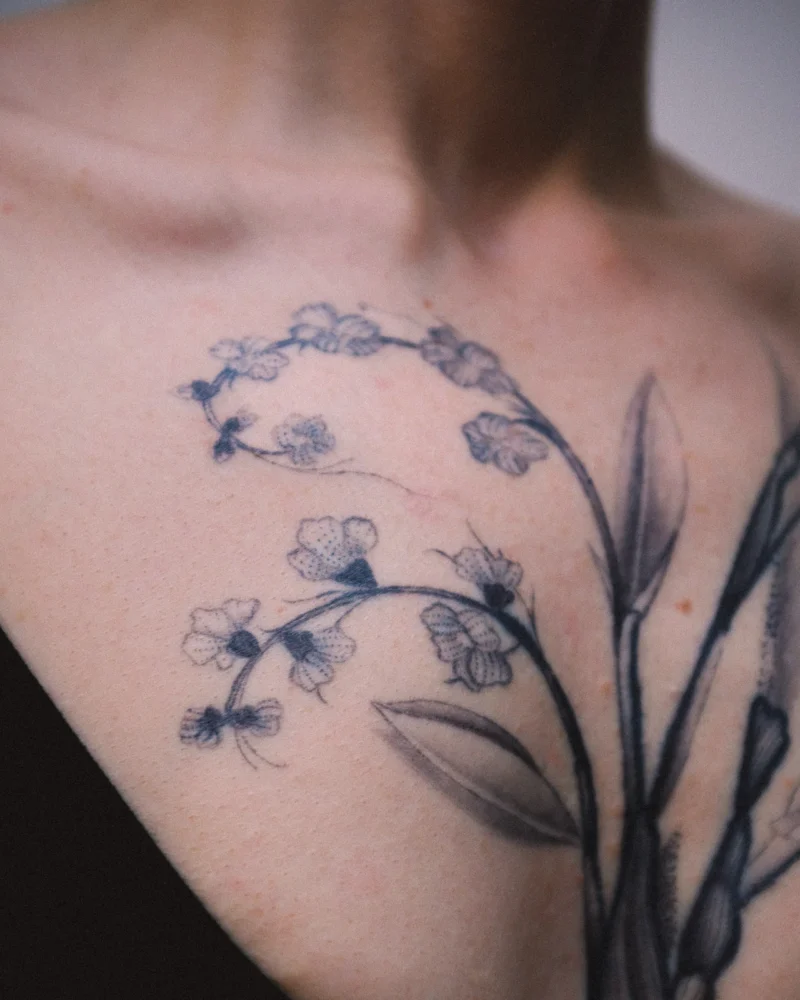 Detail view of a freehand botanical tattoo across the front torso