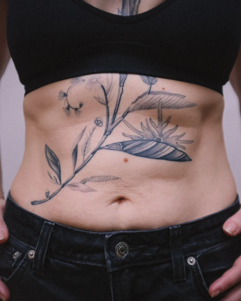 Detail view of a freehand botanical tattoo across the front torso