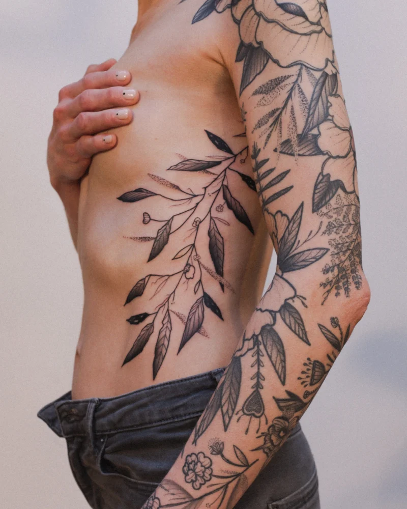 Freehand botanical tattoo across the arms and ribs