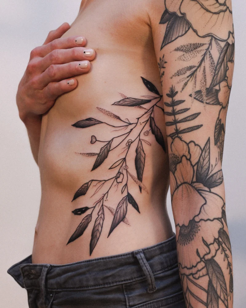 Another view of a freehand botanical tattoo across the arms and ribs
