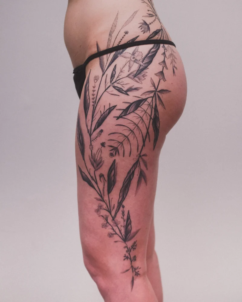 Detail view of a freehand botanical tattoo across the legs