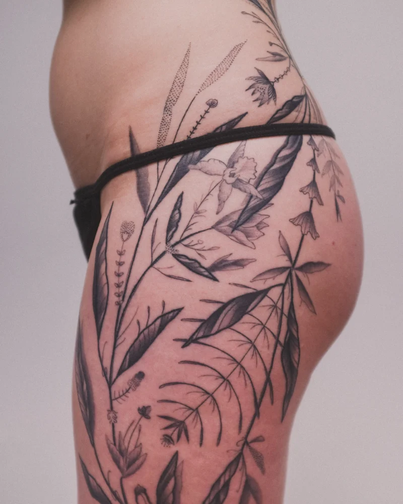 Another view of a freehand botanical tattoo across the legs