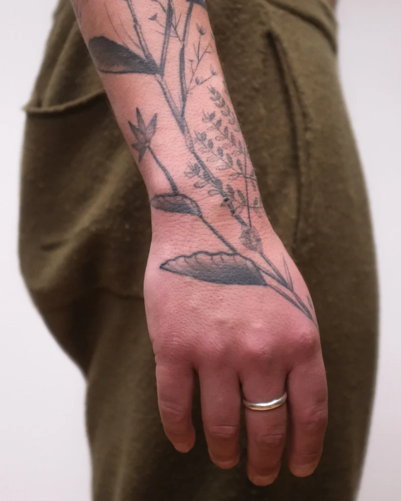 Detail view of a freehand botanical tattoo across the arms