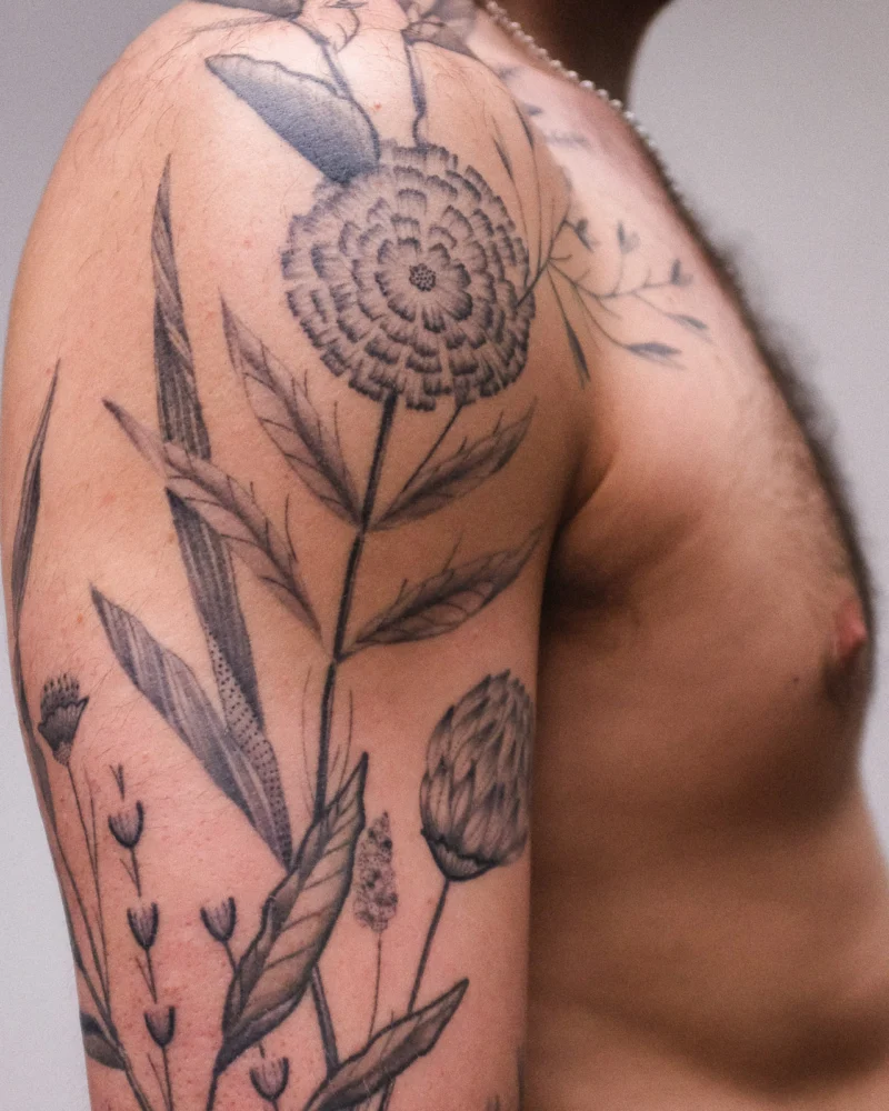 Detail view of a freehand botanical tattoo across the arms