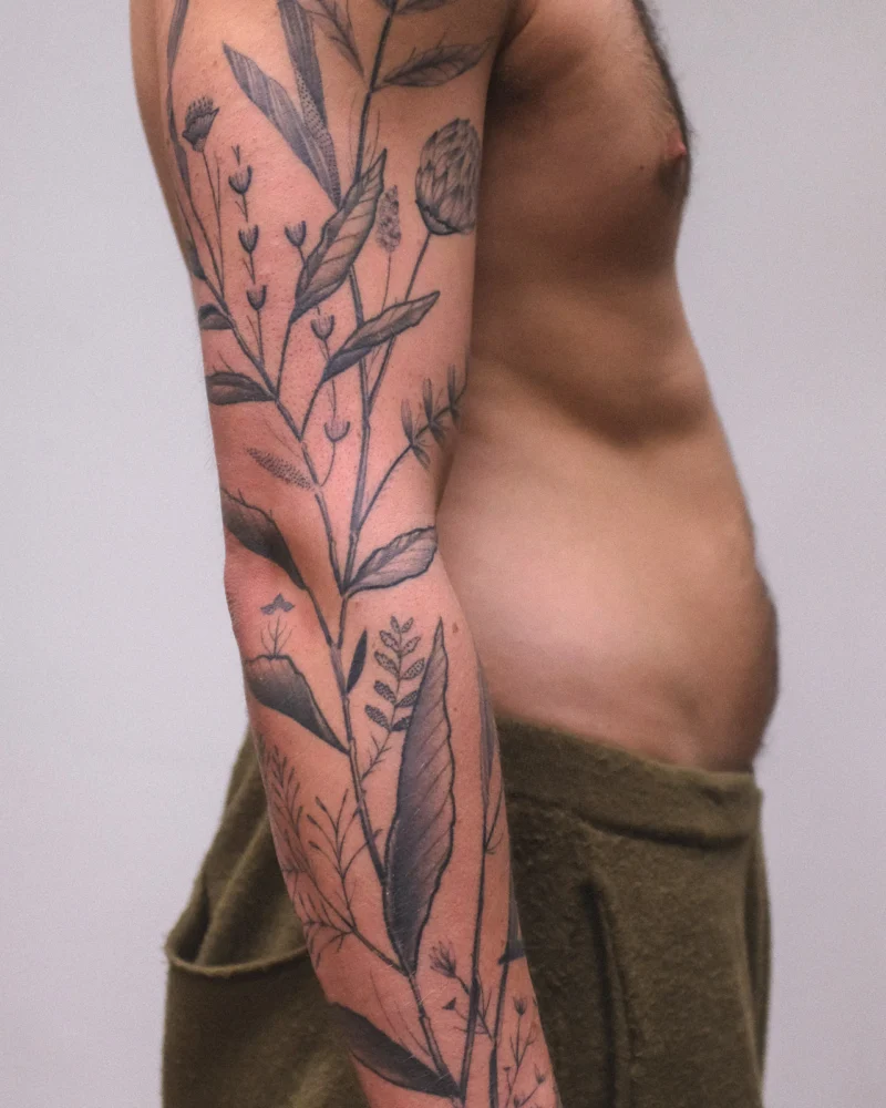 Detail view of a freehand botanical tattoo across the arms