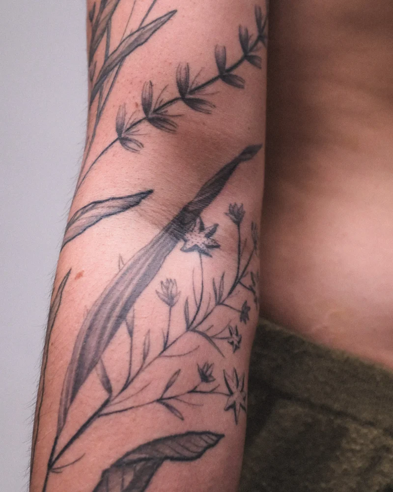 Detail view of a freehand botanical tattoo across the arms
