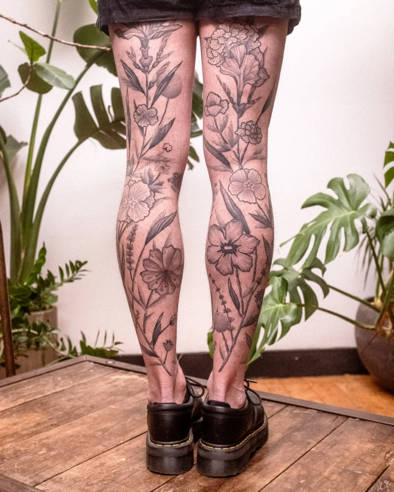 Another view of a freehand botanical tattoo across the legs