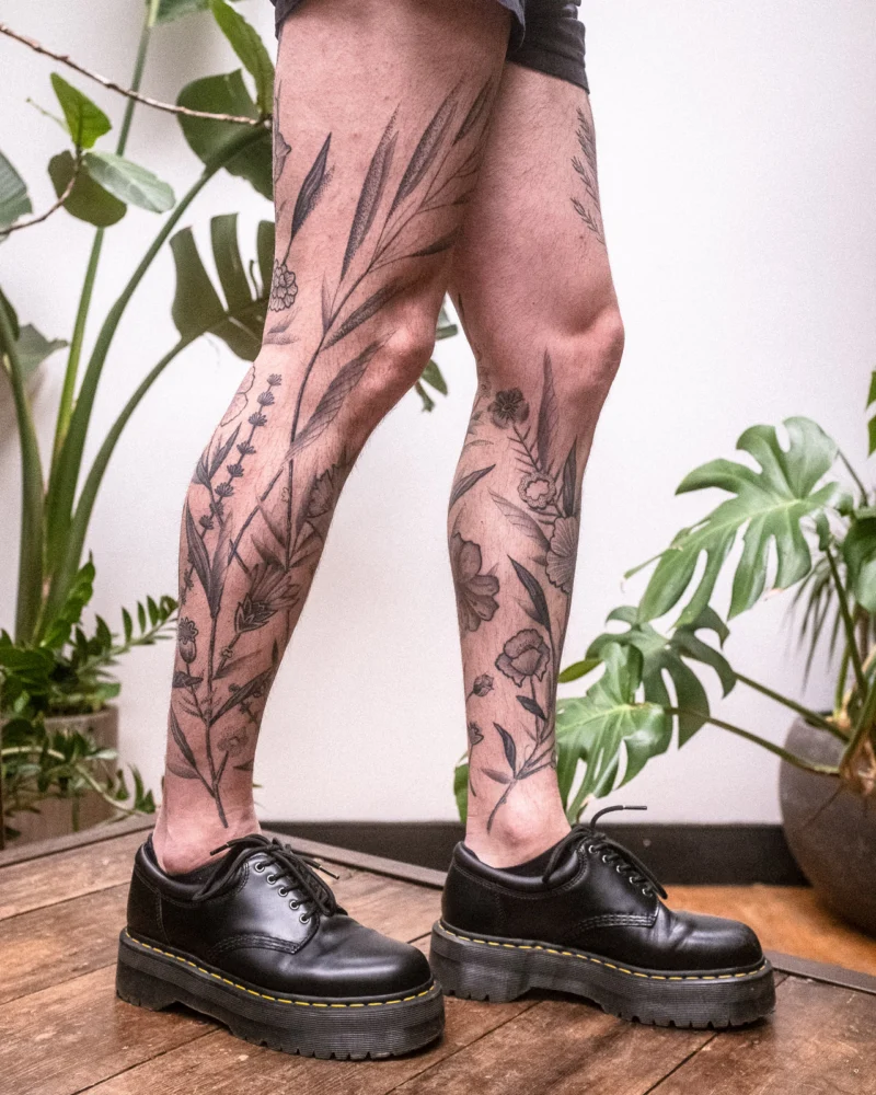 Detail view of a freehand botanical tattoo across the legs
